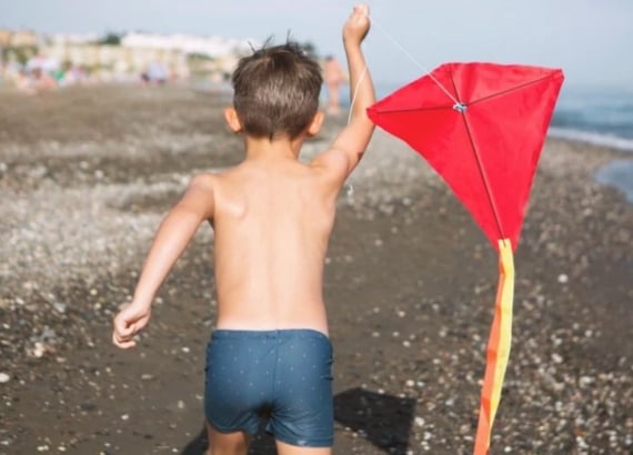 16 brincadeiras antigas para resgatar e ensinar às crianças 13 Menino brincando de empinar pipa na praia