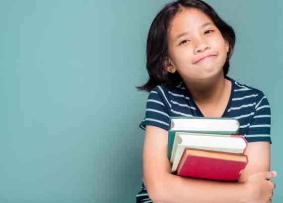 Dia do livro e dia nacional do livro infantil. Menina de 8 anos segurando livros e sorrindo