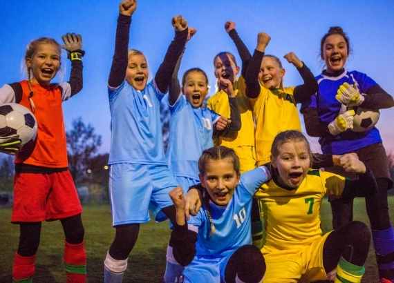 Futebol infantil. Meninas com roupas de futebol segurando bola e comemorando