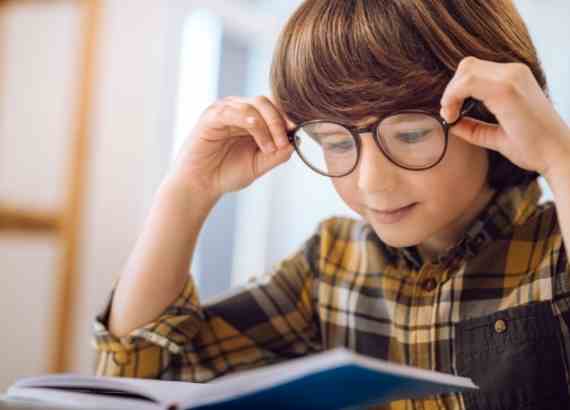 Poemas de Manuel Bandeira para crianças e características da obra do autor. Criança com óculos lendo um livro
