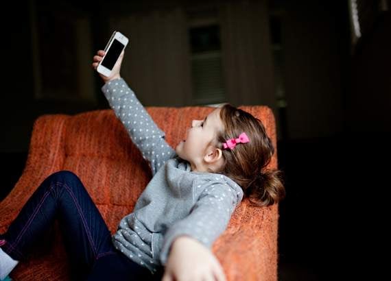 Os efeitos do TikTok em crianças e adolescentes - Menina tirando selfie no sofá