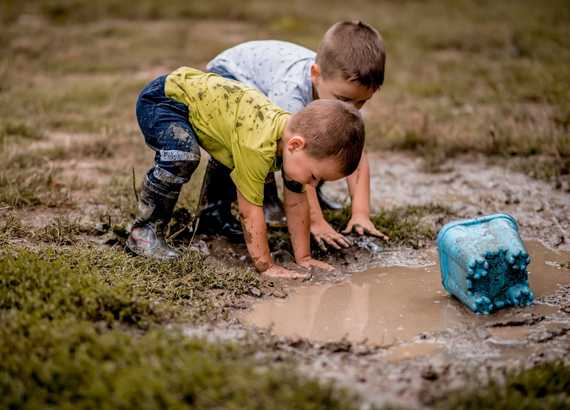 Duas crianças brincam na lama após chuva. A importância do tédio para a saúde e a criatividade 