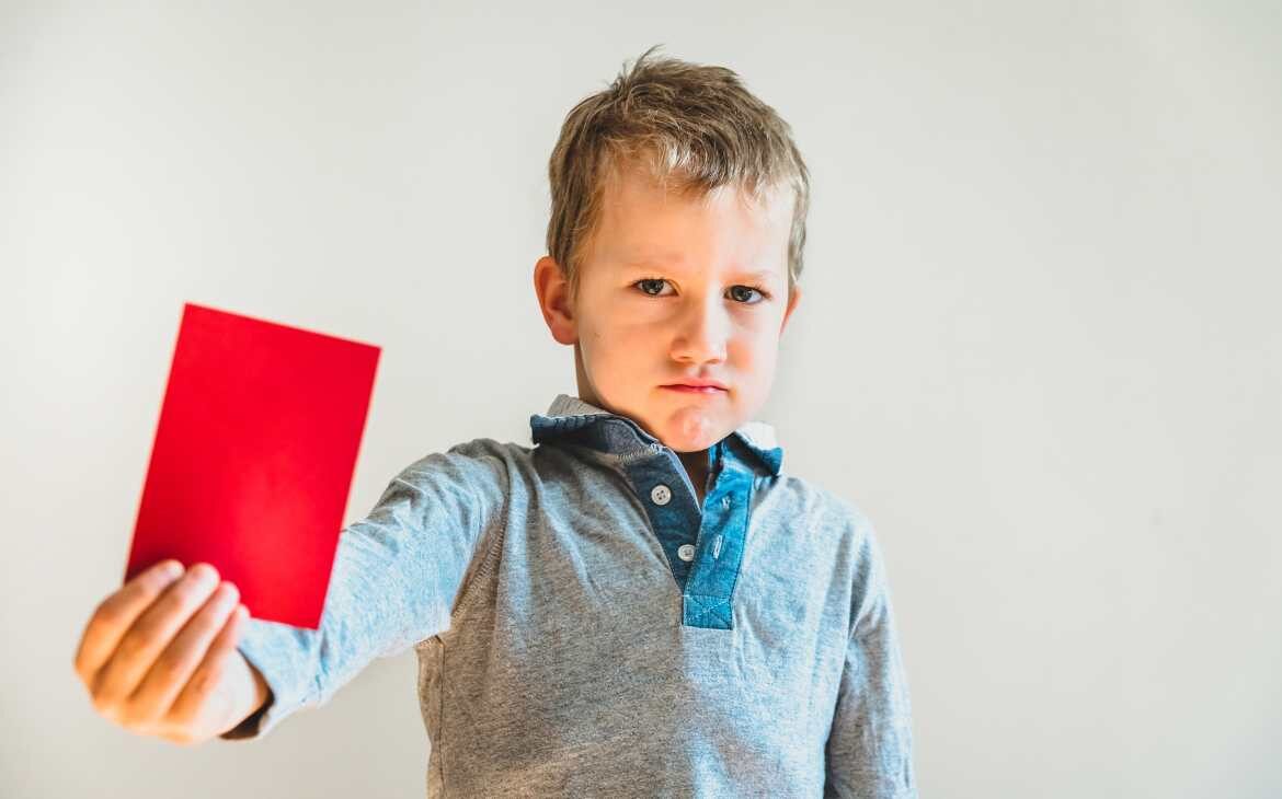 Menino mostrando um cartão vermelho com cara de rejeição. O acesso de crianças à pornografia e o que nós podemos fazer capa