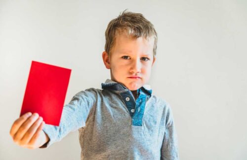 Menino mostrando um cartão vermelho com cara de rejeição. O acesso de crianças à pornografia e o que nós podemos fazer capa