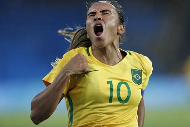 Foto de mulher com a camisa da seleção brasileira comemorando.