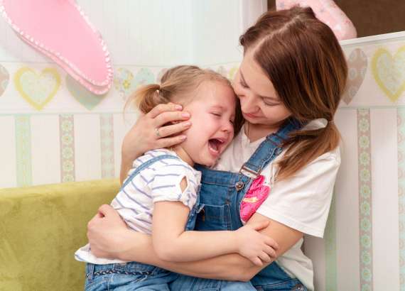 Mãe consola a filha que chora no colo
