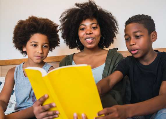 Mãe lendo um livro com filho e filha pré-adolescentes