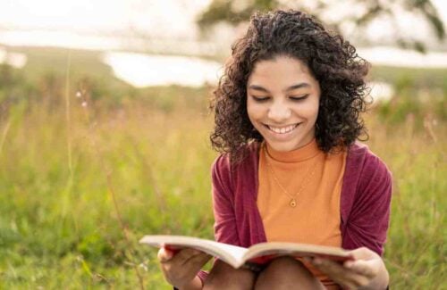 Menina adolescente lendo um livro com sorriso no rosto
