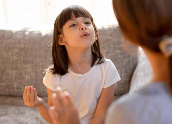 Menina dialogando com adulta fazendo gesto.