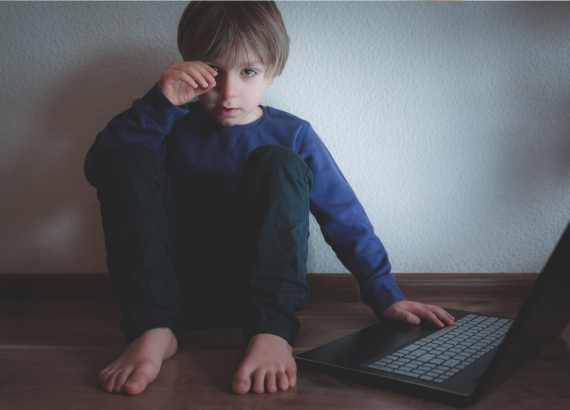 Jogos online e crianças: os perigos e cuidados nesse ambiente
Menino em notebook sentado no chão com cara muito triste.