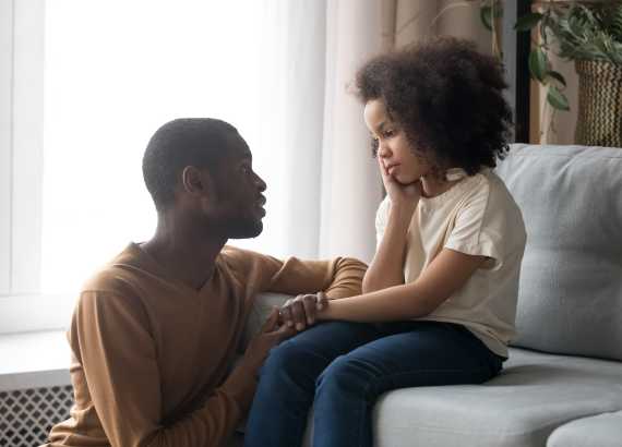O que é a depressão infantil?
Pai sentado ao chão conversando com a filha que olha para ele sentada ao sofá