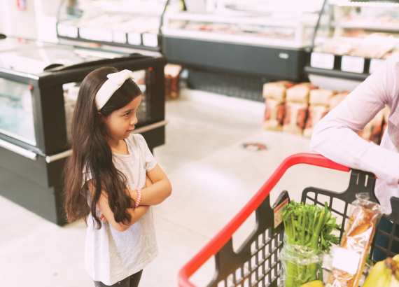 Como ensinar crianças sobre a aceitação do perder_meio. Menina de braços cruzados no mercado