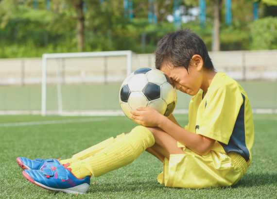 Como ensinar criancas sobre a aceitacao do perder meio. Menino triste com bola de futebol